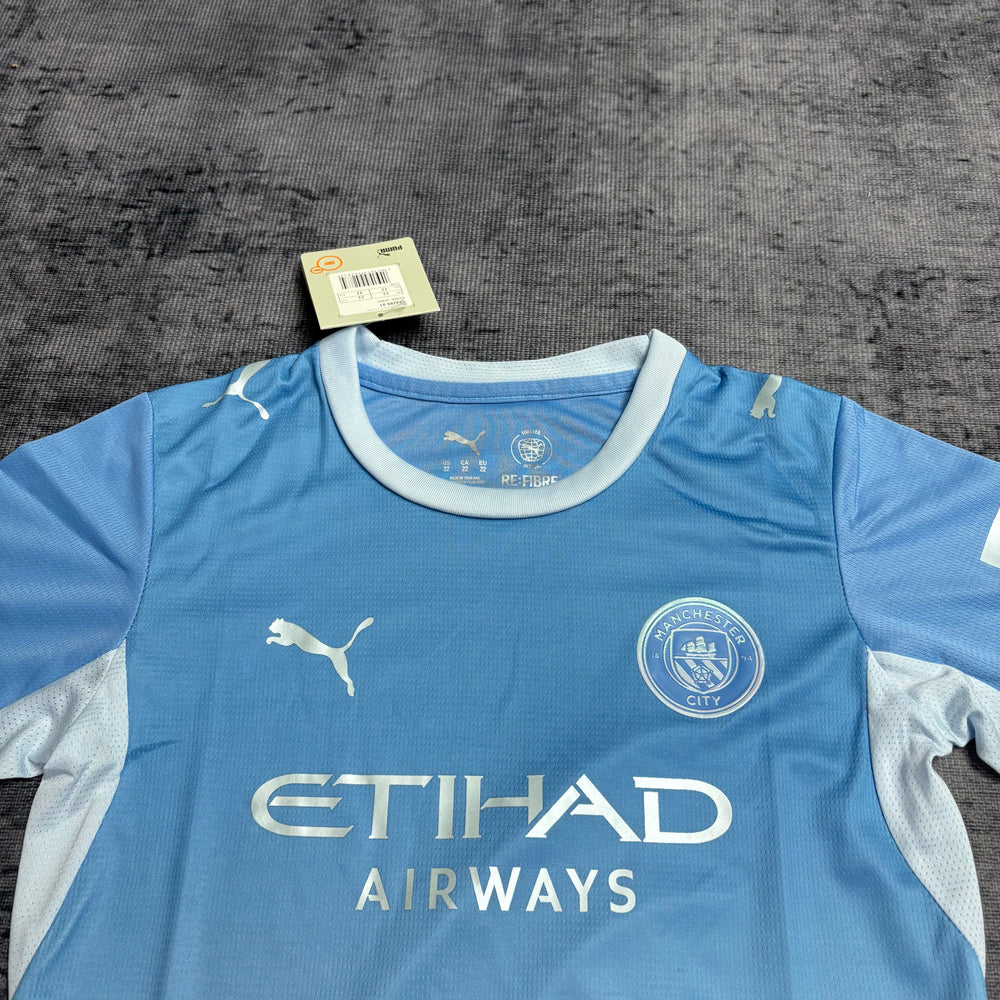 Kit Infantil Manchester City I 2026/27 Azul-Celeste Camisa e Shorts - detalhe do peito