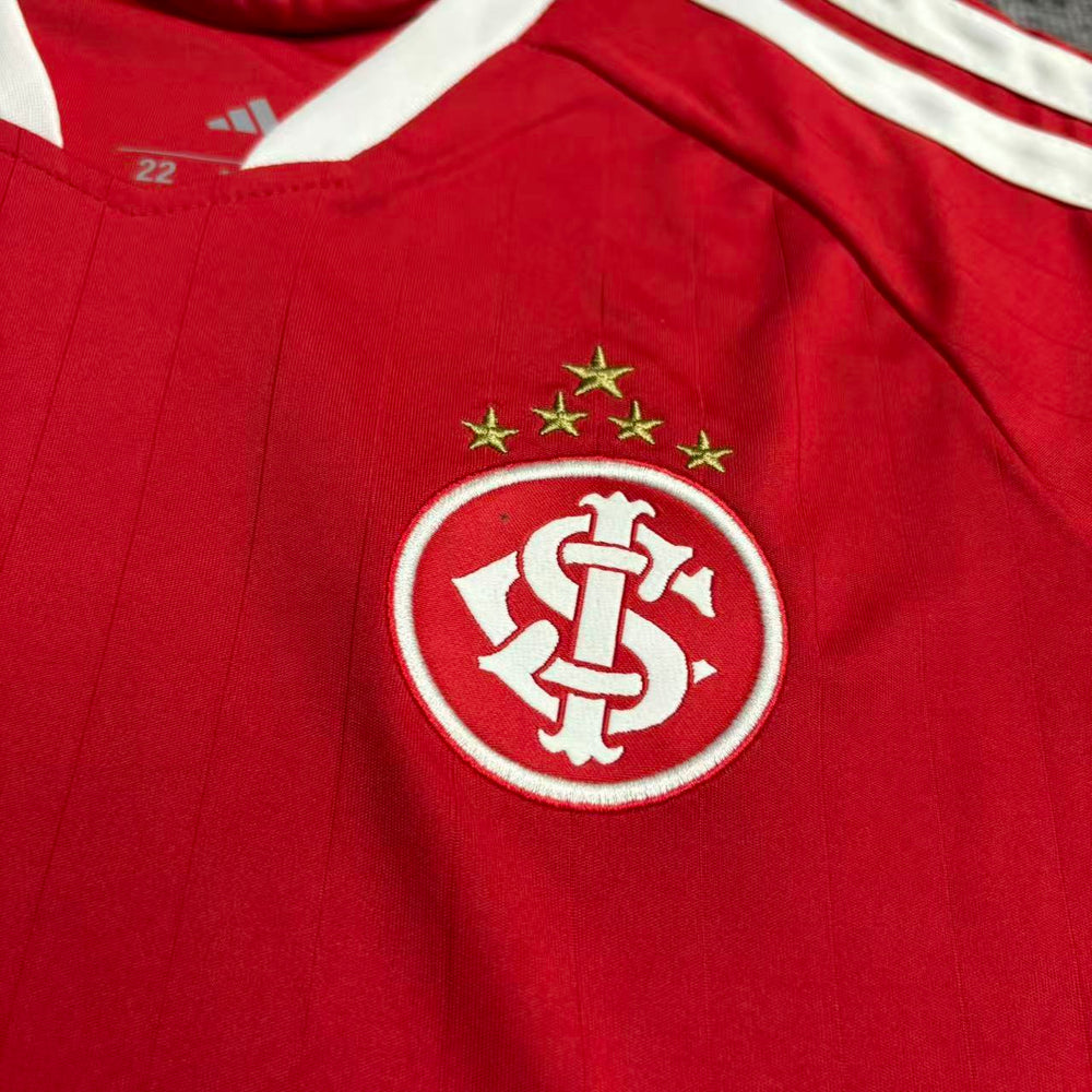 Kit Infantil Internacional I 2026/27 Vermelho Camisa e Shorts - detalhe do escudo bordado