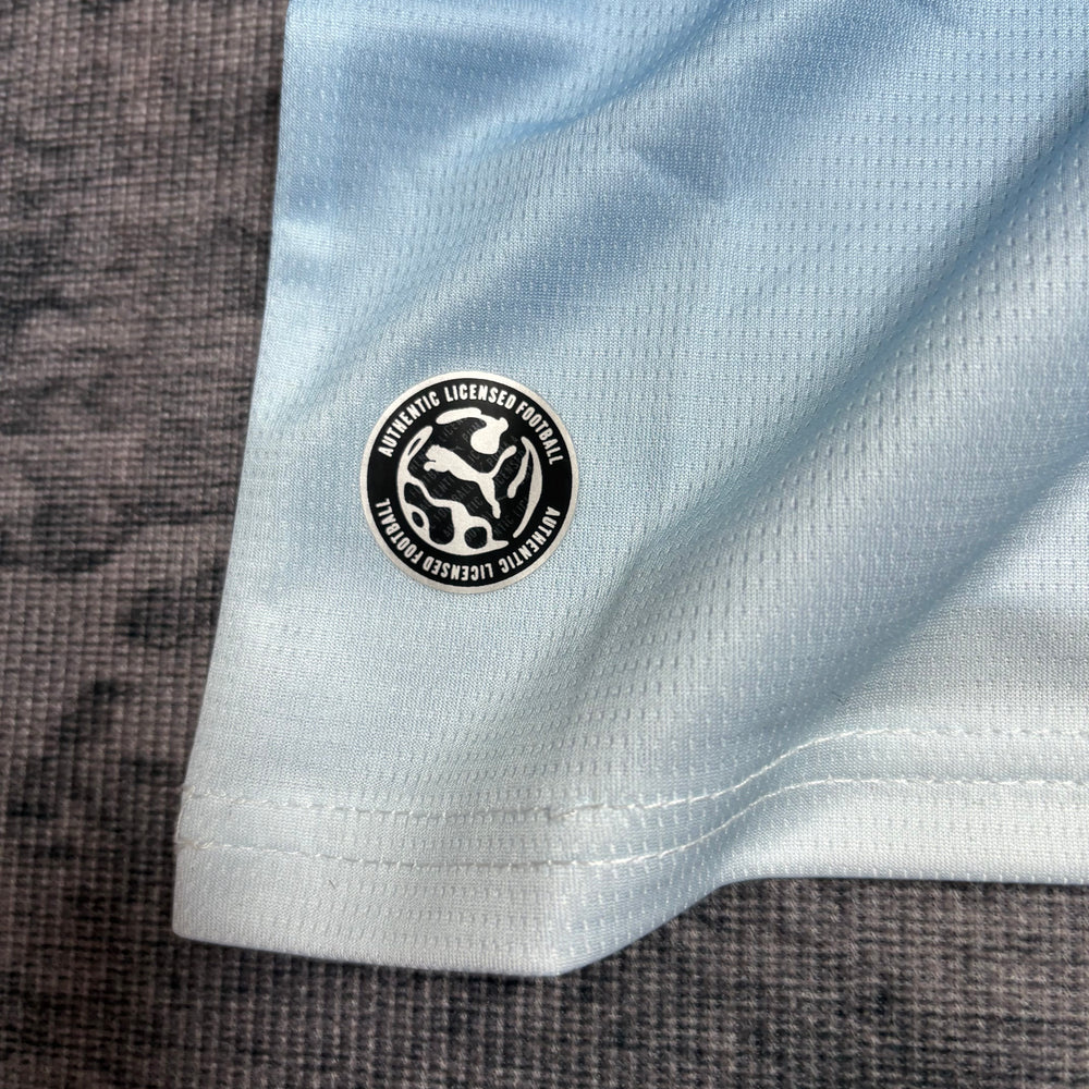 Kit Infantil Manchester City I 2026/27 Azul-Celeste Camisa e Shorts - detalhe do patch da manga