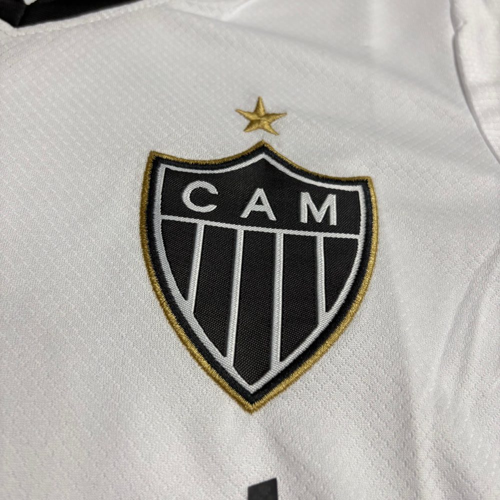 Kit Infantil Atlético Mineiro II 2026/27 Branco Camisa e Shorts - detalhe do escudo bordado